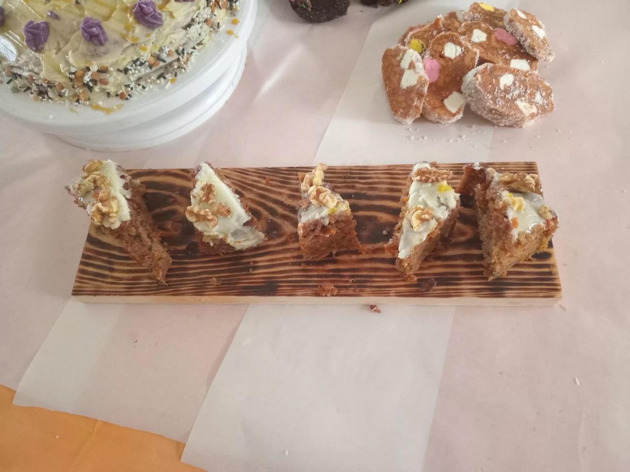 Carrot cake slices with cream cheese icing on wooden board